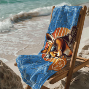 The Dirt n dust microfibre towel layed out on a timber chair, sitting on the beach sand.